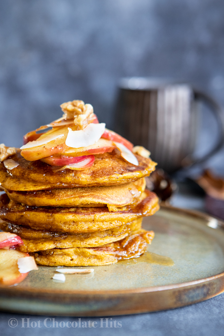 A stack of pumpkin pancakes (left), dark coffee mug in the background.