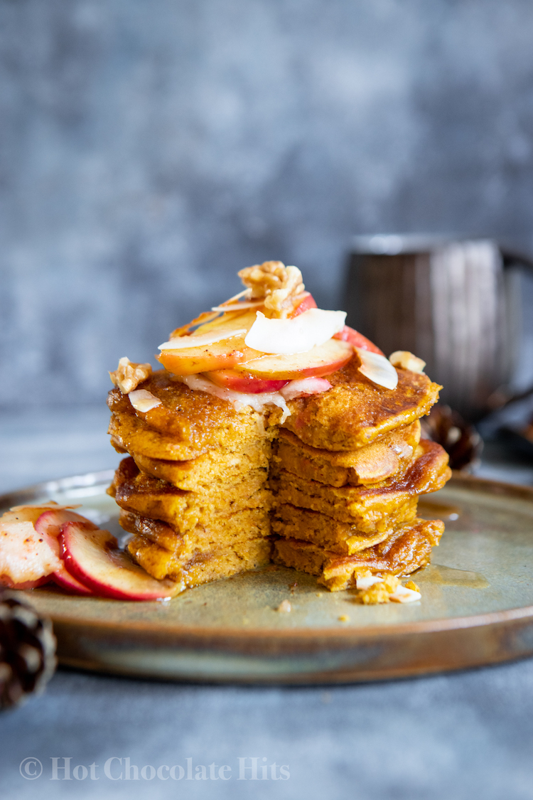 a stack of pumpkin pancakes with a piece cut out to see the inside.