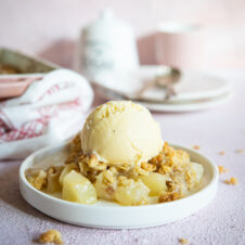 A picture of the crumble with a scoop of ice cream, dish and plates in the background