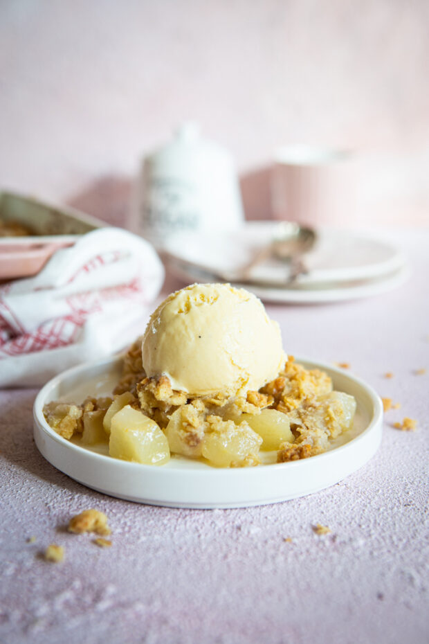 A picture of the crumble with a scoop of ice cream, dish and plates in the background