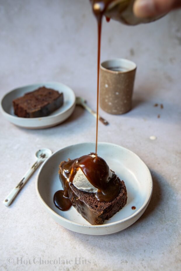 Picture of chocolate sticky toffee pudding piece with ice cream and toffee sauce (pouring shot)